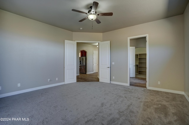 unfurnished bedroom with carpet, stainless steel fridge, a spacious closet, and ceiling fan