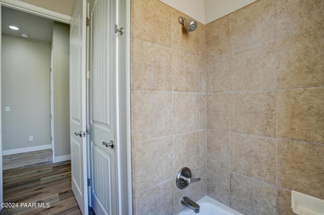 bathroom with hardwood / wood-style floors and tiled shower / bath