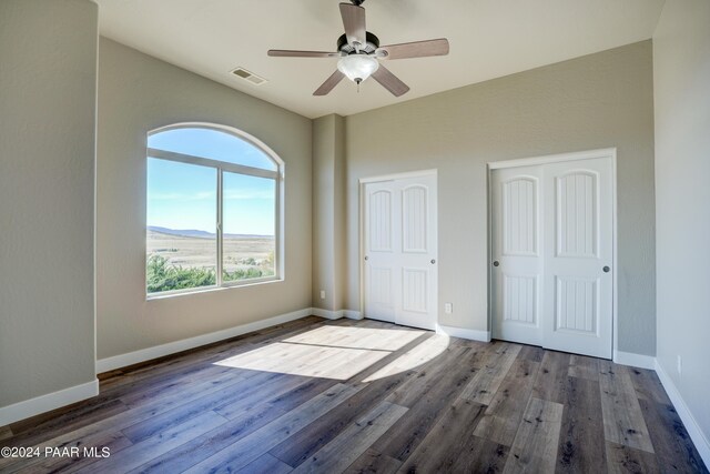 unfurnished bedroom featuring a mountain view, ceiling fan, and wood-type flooring