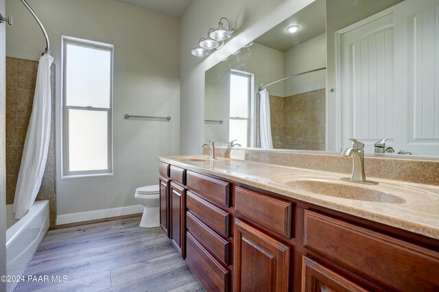 full bathroom with vanity, toilet, wood-type flooring, and shower / tub combo