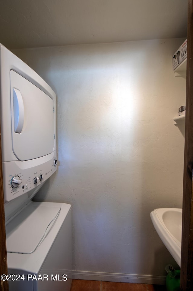 clothes washing area with tile patterned floors and stacked washer and dryer