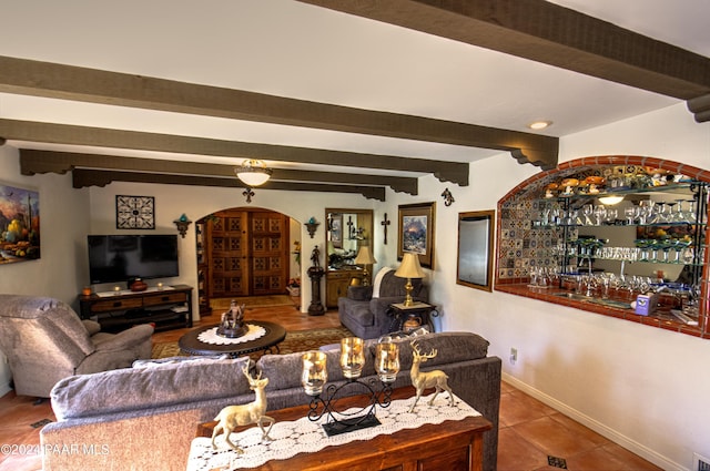 living room featuring tile patterned flooring, beamed ceiling, and indoor bar