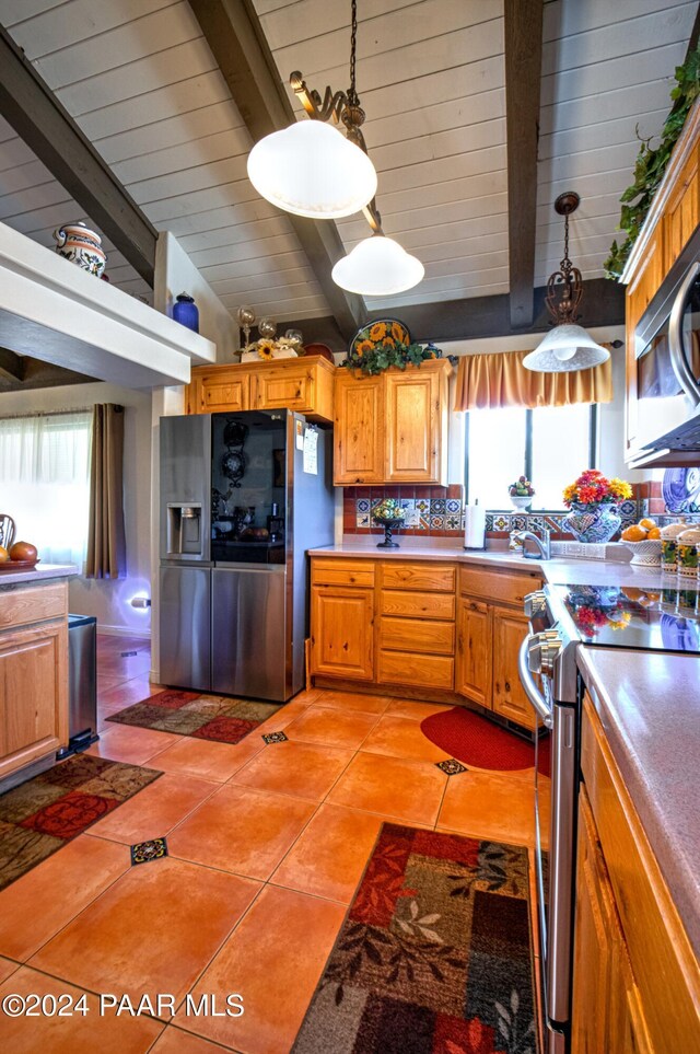 kitchen with lofted ceiling with beams, decorative light fixtures, stainless steel appliances, and a wealth of natural light