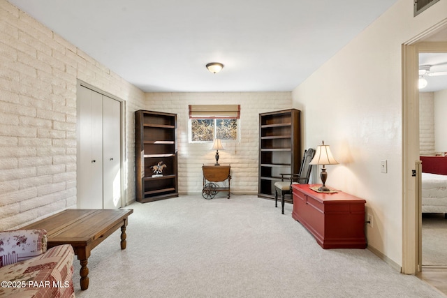 living area featuring light colored carpet and brick wall