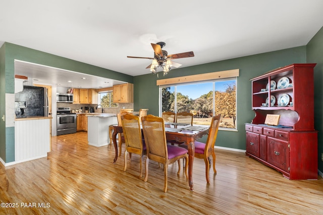 dining area with sink, light hardwood / wood-style floors, and ceiling fan