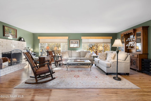 living room featuring a brick fireplace and light wood-type flooring