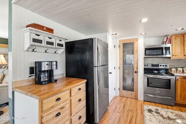 kitchen featuring appliances with stainless steel finishes, butcher block countertops, wood walls, light brown cabinets, and light wood-type flooring