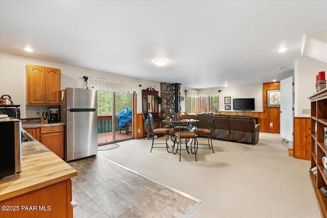 dining area with wooden walls, recessed lighting, light colored carpet, and a wainscoted wall