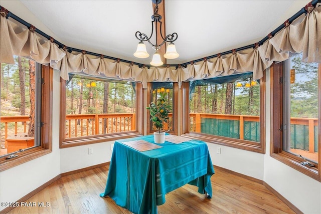 dining area with baseboards, an inviting chandelier, and hardwood / wood-style flooring