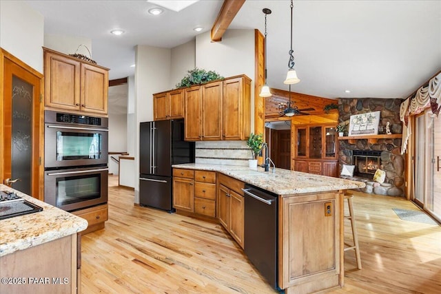 kitchen featuring a sink, high end black refrigerator, stainless steel double oven, a peninsula, and dishwashing machine