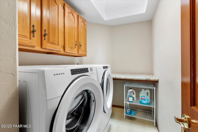 clothes washing area featuring cabinet space, light floors, and washing machine and dryer