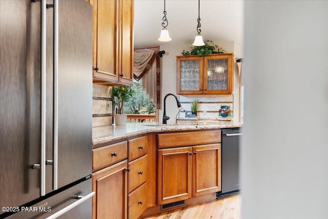 kitchen with high quality fridge, tasteful backsplash, light stone countertops, and a sink