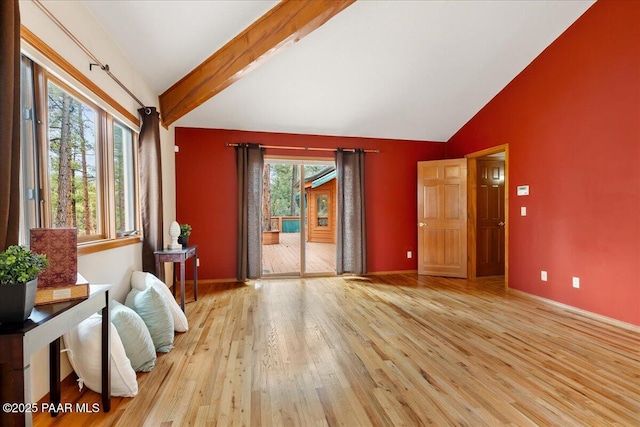 living room with baseboards, light wood-style flooring, and vaulted ceiling with beams