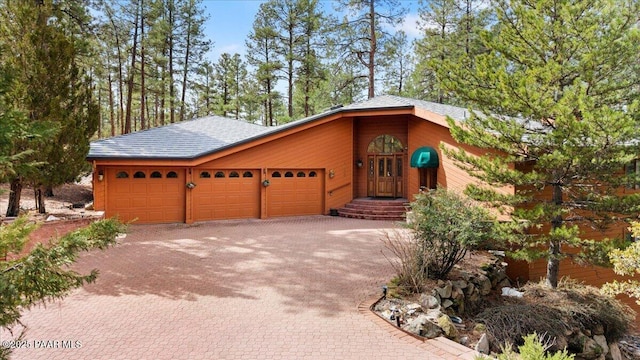 view of front of home featuring decorative driveway, an attached garage, and roof with shingles