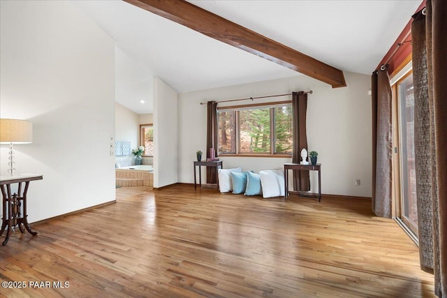 interior space with lofted ceiling with beams, baseboards, and light wood-style floors