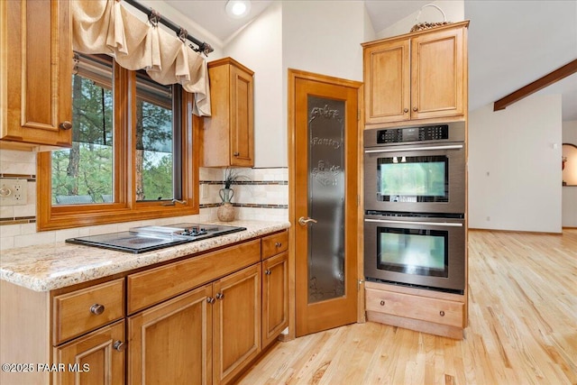 kitchen with black electric stovetop, light wood-type flooring, tasteful backsplash, and stainless steel double oven