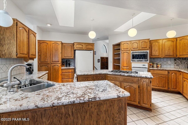 110 High Chaparral Loop, Prescott, AZ 86303 - kitchen featuring stainless steel appliances, a sink, backsplash, brown cabinets, and a center island