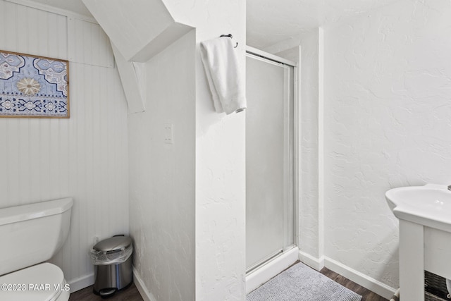 bathroom featuring toilet, an enclosed shower, wood-type flooring, and wooden walls