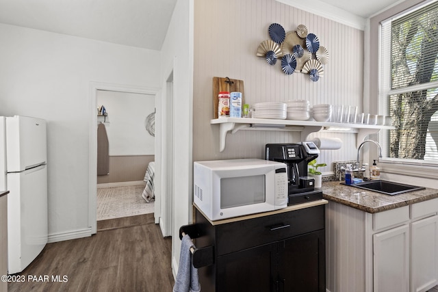 kitchen with stone counters, sink, dark hardwood / wood-style flooring, white appliances, and white cabinets