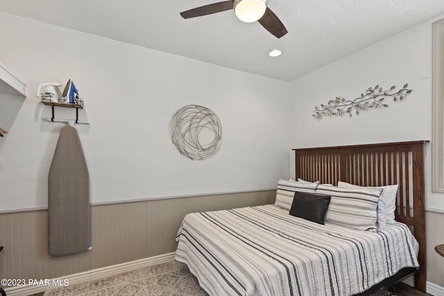 bedroom featuring ceiling fan and wainscoting