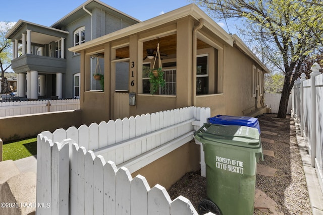 view of front of home with stucco siding, a ceiling fan, and fence