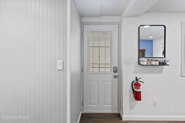 doorway featuring baseboards and dark wood-style flooring