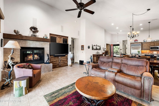 tiled living room with a fireplace, ceiling fan with notable chandelier, and a high ceiling