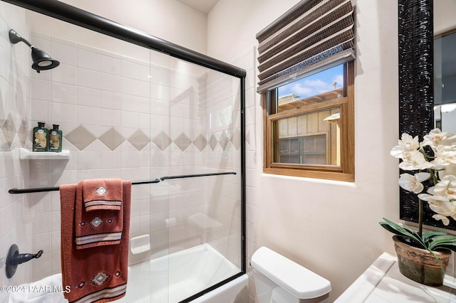 bathroom with toilet and shower / bath combination with glass door