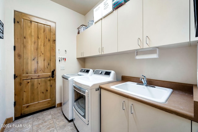 washroom featuring washing machine and clothes dryer, sink, light tile patterned floors, and cabinets