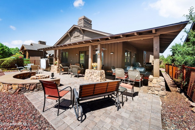 rear view of house with an outdoor living space with a fire pit and a patio