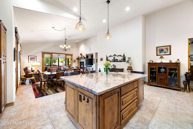 kitchen with a center island, high vaulted ceiling, hanging light fixtures, a notable chandelier, and light stone counters