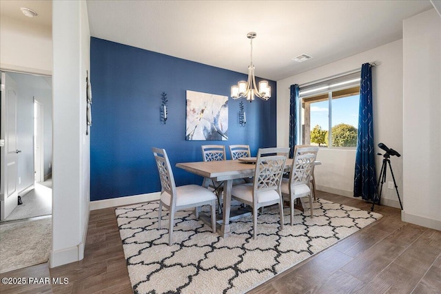 dining space featuring visible vents, a notable chandelier, wood finished floors, and baseboards
