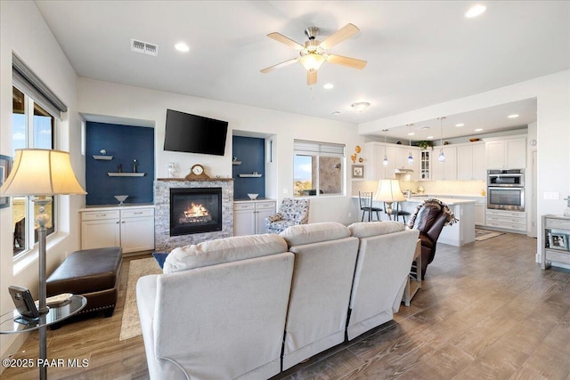 living room with visible vents, a ceiling fan, wood finished floors, recessed lighting, and a fireplace