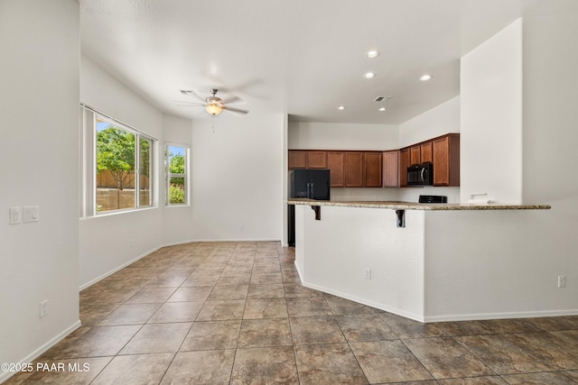 4276 N Pembroke St, Prescott Valley, AZ 86314 - kitchen with black appliances, a ceiling fan, light stone countertops, a breakfast bar area, and recessed lighting