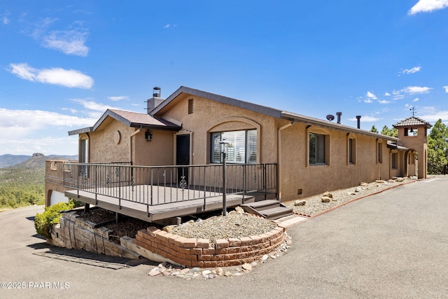 5712 W Sunrise Dr, Prescott, AZ 86305 - single story home featuring stucco siding, a chimney, a deck with mountain view, and concrete driveway