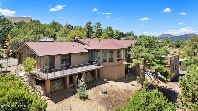 5712 W Sunrise Dr, Prescott, AZ 86305 - view of front of home with a sunroom, stone siding, a deck, and a shingled roof