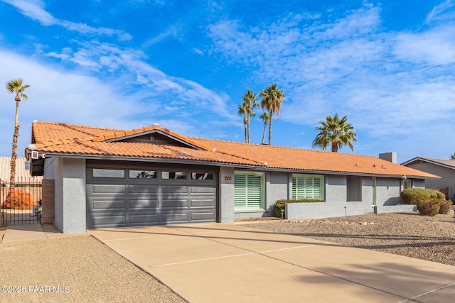 single story home with stucco siding, a garage, driveway, and fence