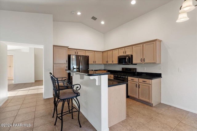 kitchen featuring light brown cabinetry, stainless steel appliances, high vaulted ceiling, and an island with sink