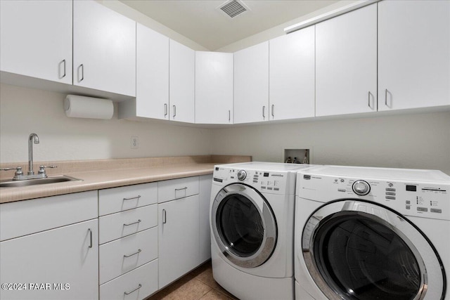 laundry area featuring washer and dryer, light tile patterned floors, cabinets, and sink