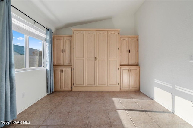 interior space with light tile patterned floors and lofted ceiling