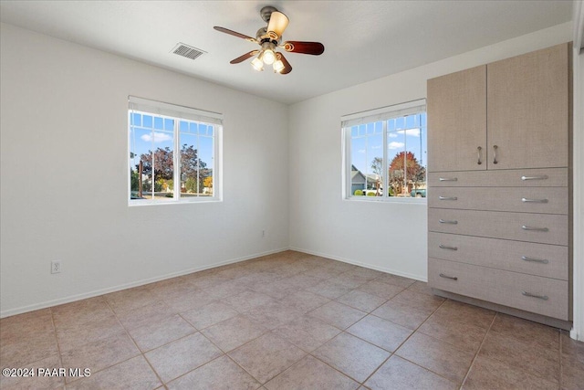 tiled empty room with ceiling fan and a healthy amount of sunlight