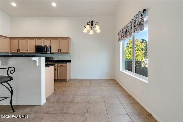 kitchen featuring light brown cabinetry, pendant lighting, light tile patterned floors, an inviting chandelier, and a breakfast bar area