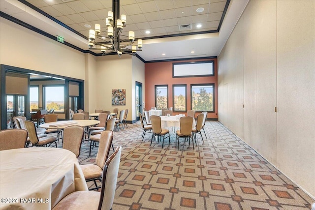 dining area with a notable chandelier, light colored carpet, ornamental molding, and a high ceiling