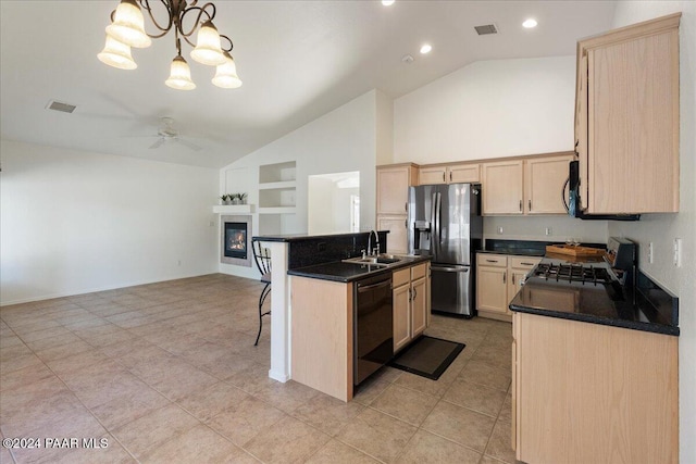 kitchen featuring a kitchen island with sink, black appliances, light brown cabinets, decorative light fixtures, and lofted ceiling