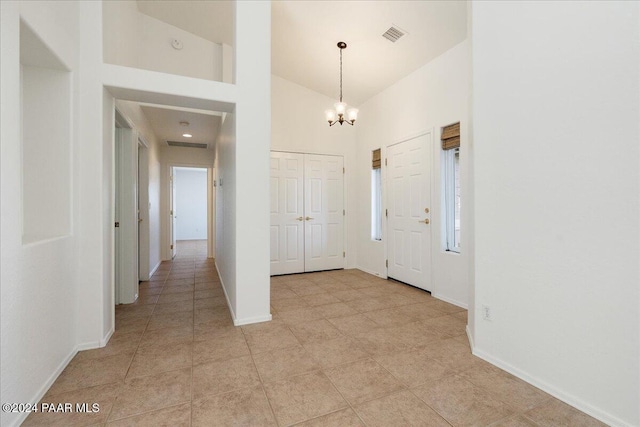 foyer featuring light tile patterned floors, high vaulted ceiling, and a chandelier