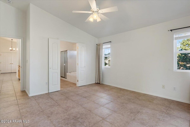 spare room with ceiling fan with notable chandelier, light tile patterned floors, lofted ceiling, and a healthy amount of sunlight