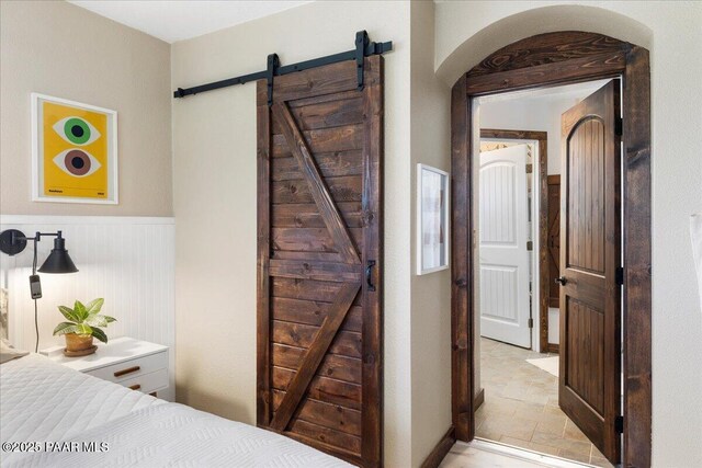714 Mingus Ave, Prescott, AZ 86301 - bedroom with a barn door, arched walkways, and a wainscoted wall