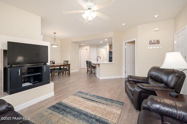 living room featuring ceiling fan, sink, and light hardwood / wood-style flooring