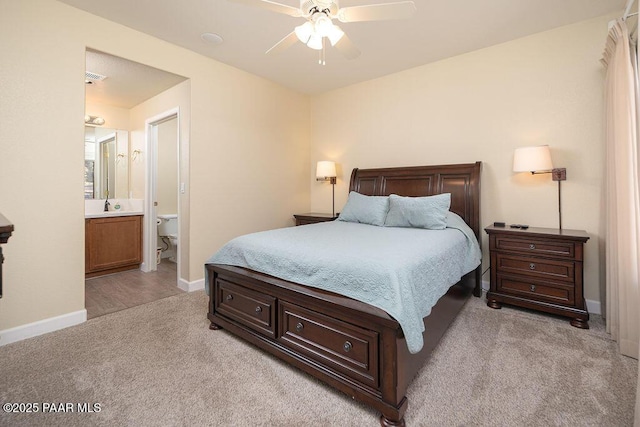 bedroom with ensuite bathroom, ceiling fan, light colored carpet, and sink