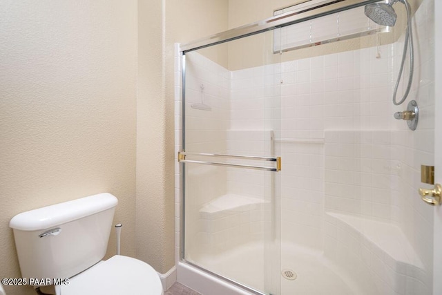 bathroom featuring toilet and a shower with door